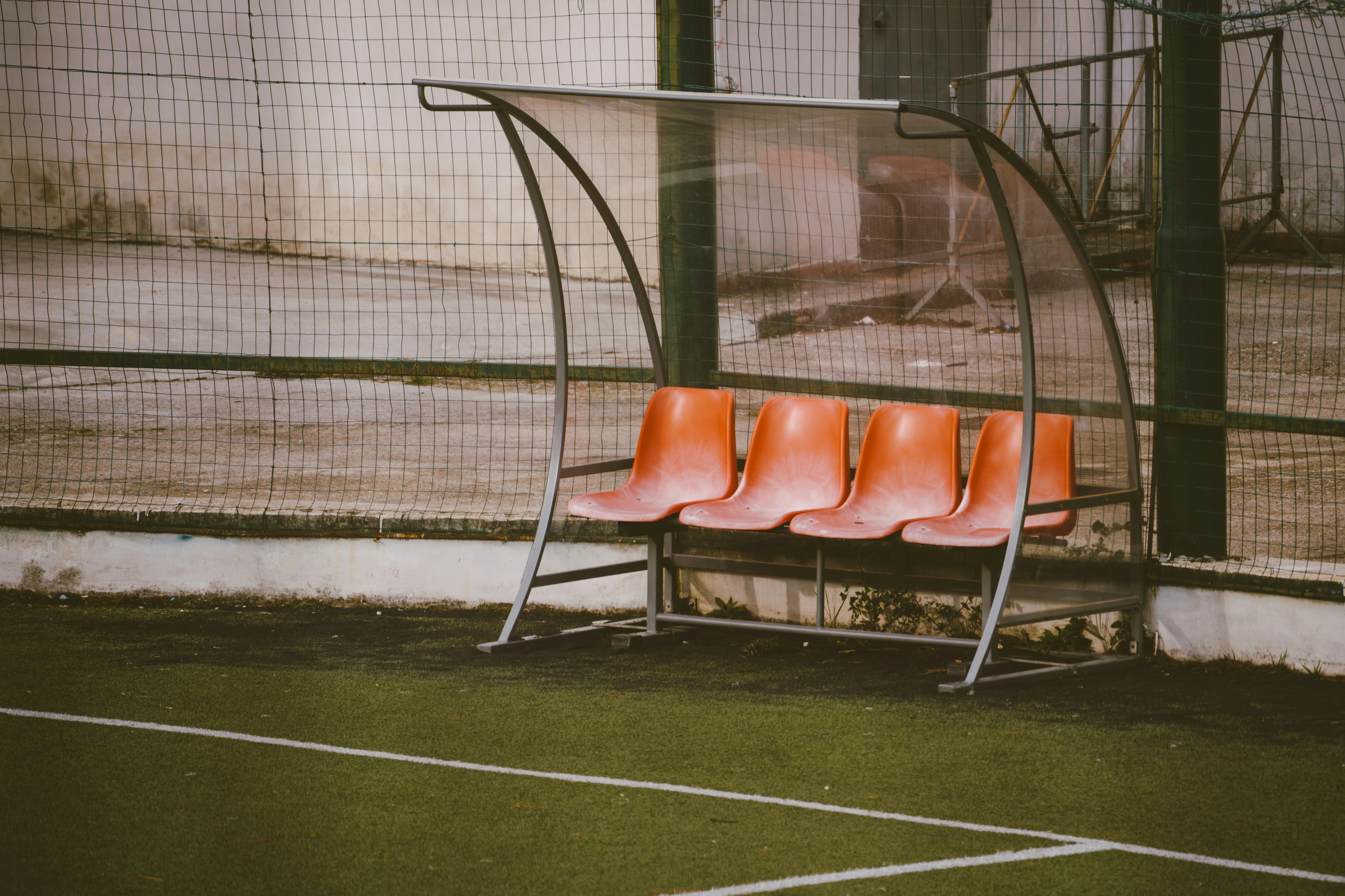 a row of orange chairs sitting on top of a tennis court